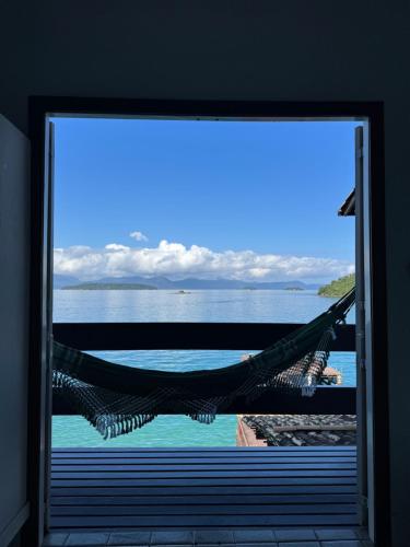a hammock in a room with a view of the water at Pousada Casa do Bicho Preguiça in Angra dos Reis