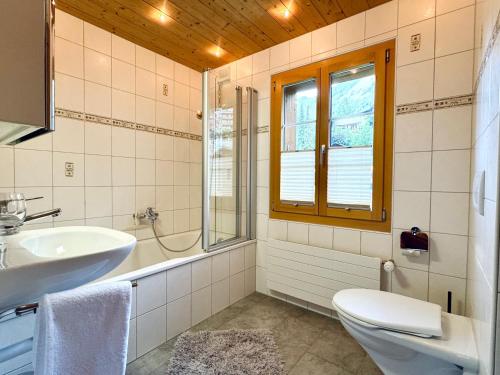 a bathroom with a sink toilet and a window at Chalet Im Bätzenboden in Wengen