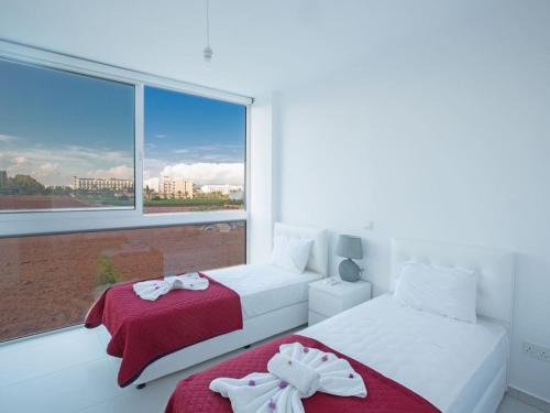 ein weißes Schlafzimmer mit zwei Betten und einem Fenster in der Unterkunft Villa Panemorfi - Luxury Brand New 3 Bedroom Protaras Villa With Private Pool in Protaras