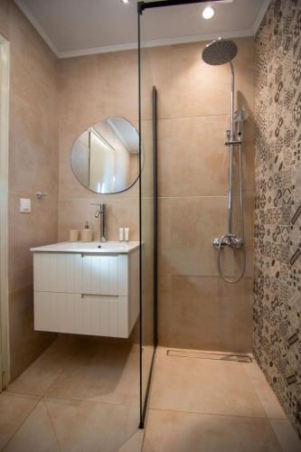 a bathroom with a sink and a shower with a mirror at Perdika center rooms in Pérdika