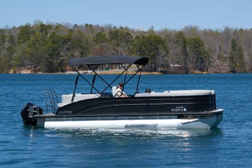 a man in a black and white boat on the water at DockTales - Panoramic Views & Private Dock in Six Mile