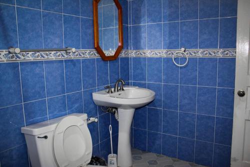 a blue tiled bathroom with a toilet and a sink at Casa de huéspedes la guarecita in Pátzcuaro
