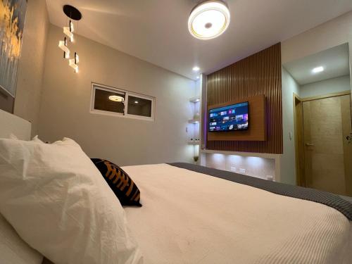a bedroom with a bed with a tv on the wall at Santana Building in San Pedro de Macorís