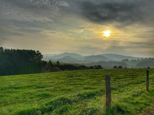 a fence in a field with the sun in the sky at Flechtdorfer Waldblick - 130 qm großes Ferienhaus und großem Grundstück und Bachlauf und Terrasse für 6 Gäste in Diemelsee