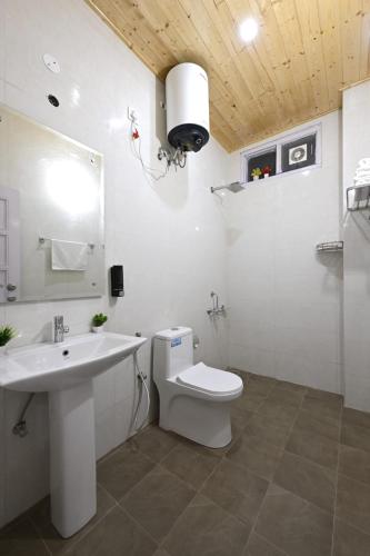 a white bathroom with a sink and a toilet at DUSK VIBES near mall roade kasauli Entire 1-bedroom with private balcony with delicious food in Kasauli