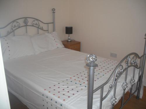 Una cama blanca con lunares rojos. en The Blue House Apartments, en Bushmills