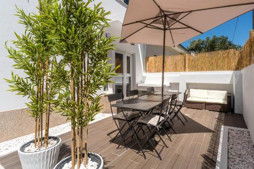 een terras met een tafel, stoelen en een parasol bij GuestReady - Fantastic family home in Salgueiros in Porto