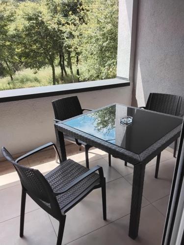 a table and chairs on a balcony with a window at Apartmani Sutomore Tri Palme in Sutomore