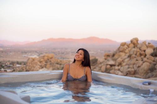 a woman sitting in a hot tub with a view at Fox Inn Epic Views, Hot Tub, Cowboy Tub, Grill in Yucca Valley