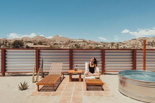 a woman sitting in a chair on the roof of a house at Fox Inn Epic Views, Hot Tub, Cowboy Tub, Grill in Yucca Valley
