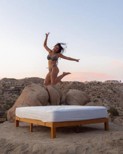 a woman jumping on a bed on the beach at Fox Inn Epic Views, Hot Tub, Cowboy Tub, Grill in Yucca Valley