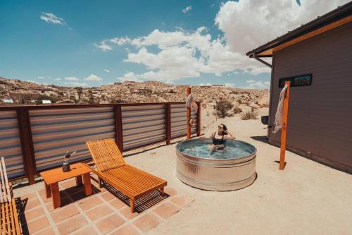 a woman sitting in a hot tub on a patio at Fox Inn Epic Views, Hot Tub, Cowboy Tub, Grill in Yucca Valley