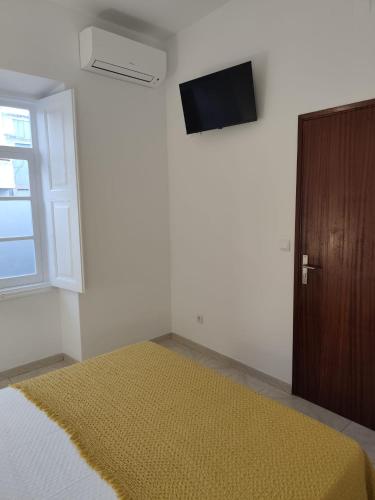 a bedroom with a bed and a tv on the wall at Simply House in Faro