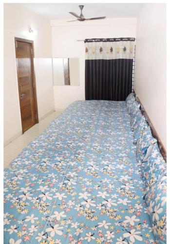 a bedroom with a bed with a blue floral bedspread at Manibhadra home stay in Ujjain