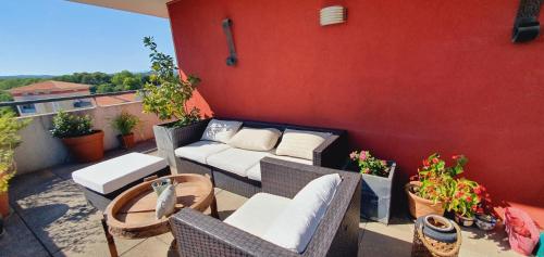 d'une terrasse avec un canapé et des chaises sur un balcon. dans l'établissement Nouveau T3 Caudalie Piscine Proche Montpellier et Plages, à Montferrier-sur-Lez