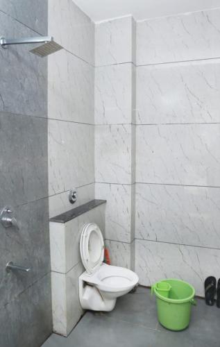 a bathroom with a toilet and a green bucket at Manibhadra home stay in Ujjain