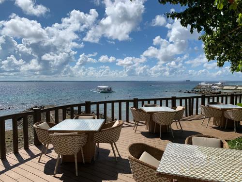 a deck with tables and chairs and the ocean at 180 degree ocean view apartment in Punta Engaño