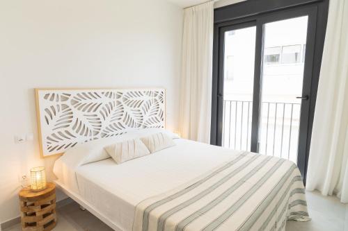 a white bedroom with a bed and a large window at Tarifa Cozy House - Casa Verde Agua in Tarifa