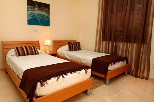 deux lits dans une chambre avec une fenêtre dans l'établissement Aphrodite Hills Superior Villas Superior Villa 0066 Air Conditioning, à Paphos