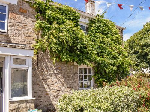 a stone house with ivy on the side of it at Churchtown Cottage in Cubert