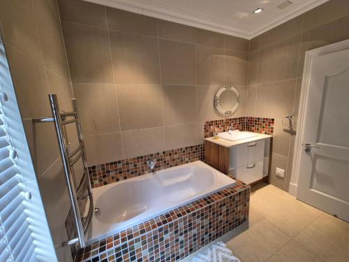 a bathroom with a large tub and a sink at Jumanji Safaris Villa Constantia in Cape Town