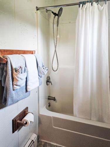 a bathroom with a shower with a white shower curtain at Katahdin Valley Motel in Sherman