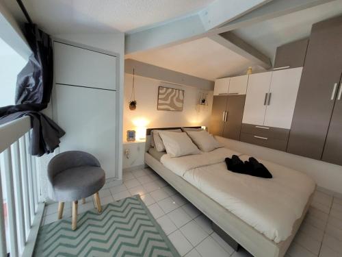 a bedroom with a bed and a chair in it at Charmant T1 climatisé avec Terrasse & Accès Piscine in Le Lavandou