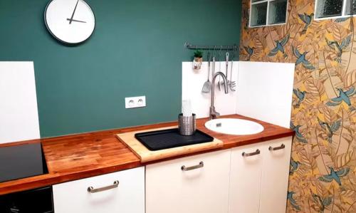 a kitchen with a sink and a clock on the wall at Location Bassin Arcachon in Le Teich