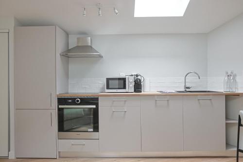 une cuisine avec des armoires blanches et un micro-ondes dans l'établissement Le Castéja Chic - Elégance en Centre Ville, à Bordeaux