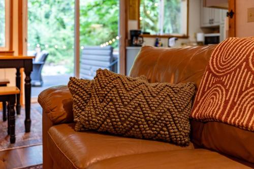 a brown leather couch with a pillow on it at NWPADS-Verlot River Cabin - Hot Tub-Firepit-Beach in Granite Falls
