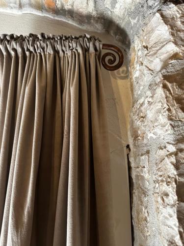 a curtain in a room with a stone wall at Nido di Gufi in Todi