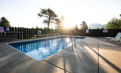 a swimming pool with the sun setting behind a fence at Saddle & Surrey Motel in Estes Park