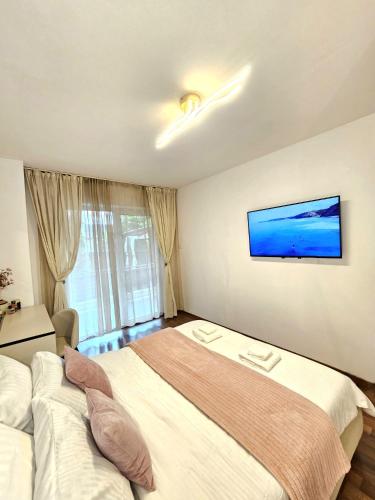 a bedroom with a bed and a tv on the wall at The Solstice Garden Suites in Cluj-Napoca