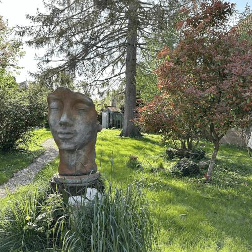 Una statua di una testa seduta nell'erba di Au Clos de Charny a Charny