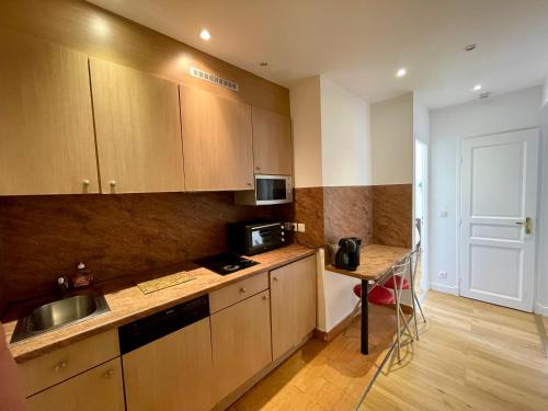 La cuisine est équipée de placards en bois, d'un évier et d'un four micro-ondes. dans l'établissement Appartement Tour Eiffel Maison de la Radio, à Paris