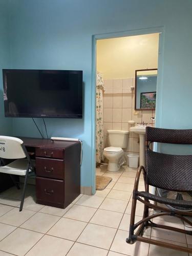 a bathroom with a toilet and a tv on the wall at Tucan Studio Ocotal in Coco
