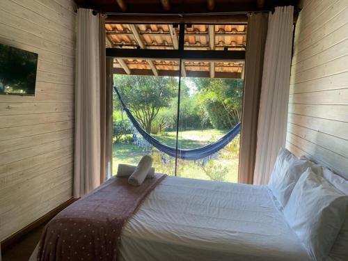 a bedroom with a bed in front of a window at Pousada Watu Kerere in Praia do Rosa