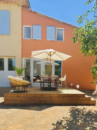 a patio with an umbrella and a table and chairs at NOUS in Agel