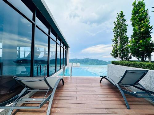 two chairs sitting on a deck next to a swimming pool at Explore Penang Stay Style w Sky pool Sea airport 9pax in Bayan Lepas