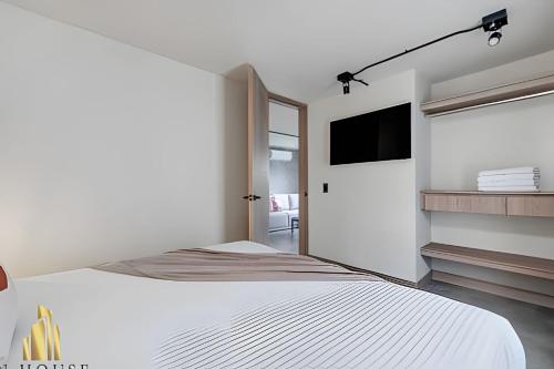 a white bedroom with a bed and a flat screen tv at Casa Solei 12-7 - Bright & Chic Apt in Manila / AC in El Poblado