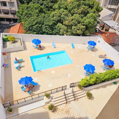 an overhead view of a pool with chairs and blue umbrellas at Flat in Copacabana in Rio de Janeiro