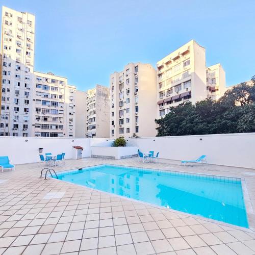 a swimming pool with blue chairs and buildings at Flat in Copacabana in Rio de Janeiro