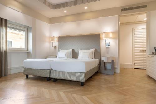 a large bedroom with a large white bed with white pillows at Meliá Genova in Genova