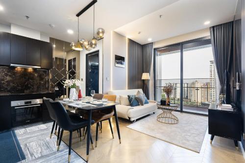 a kitchen and living room with a table and a couch at Lumiere Riverside Heera Stay Apartment in Ho Chi Minh City