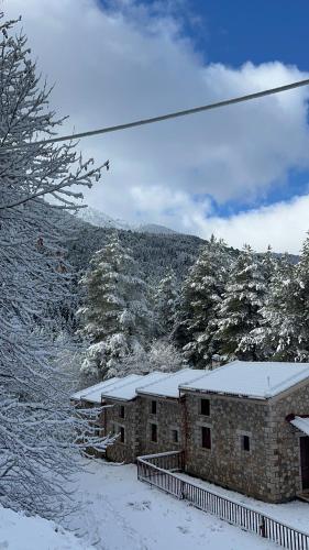 a building covered in snow with a mountain in the background at Konstantina 2 in Ayía Varvára