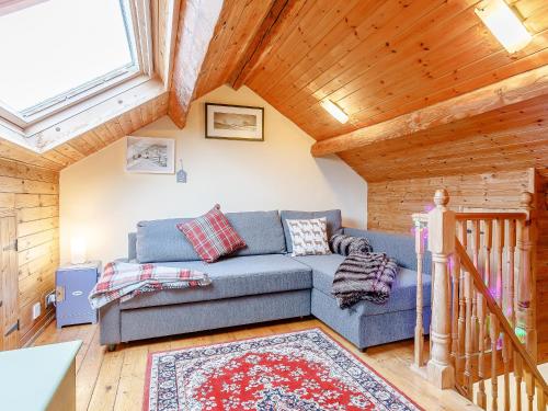 a living room with a blue couch and a wooden ceiling at The Hayloft in Glossop
