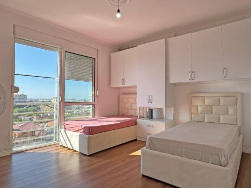 a bedroom with two beds and a large window at Ilir Daily Rent in Durrës