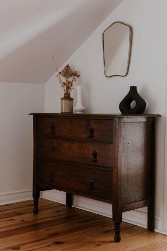 a wooden dresser with a mirror on a wall at The Wild Rose - Cozy PEC Rental in Picton in Picton