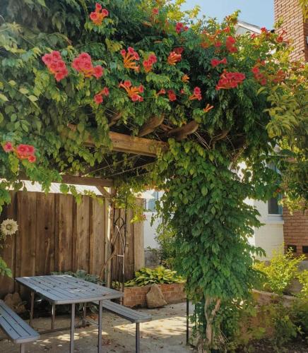 a pergola with a table and flowers on it at The Wild Rose - Cozy PEC Rental in Picton in Picton