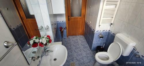a bathroom with a toilet and a sink with flowers at 2 rooms Condo near Zoom Beach in Constanţa